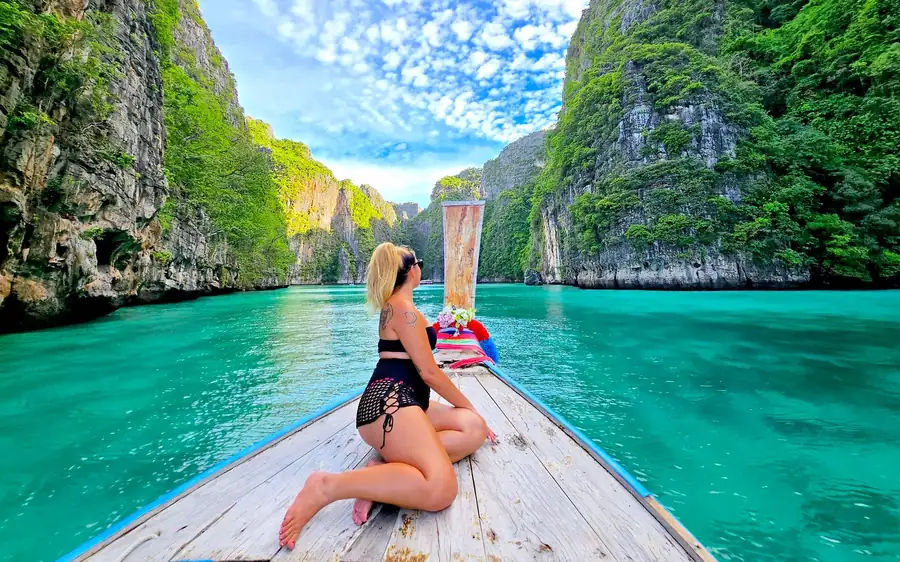 The long wooden bow of a private longtail boat on a green lagoon