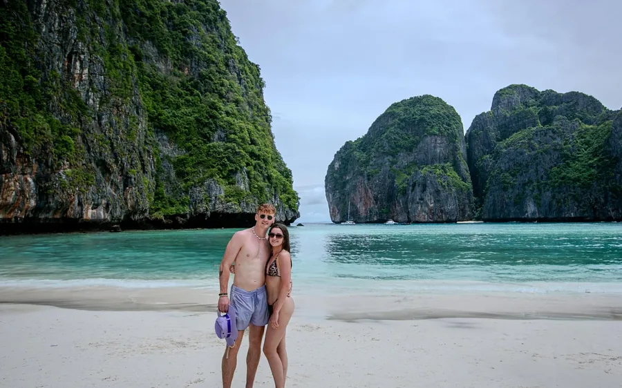 Two people standing on a white sand beach below the cliffs